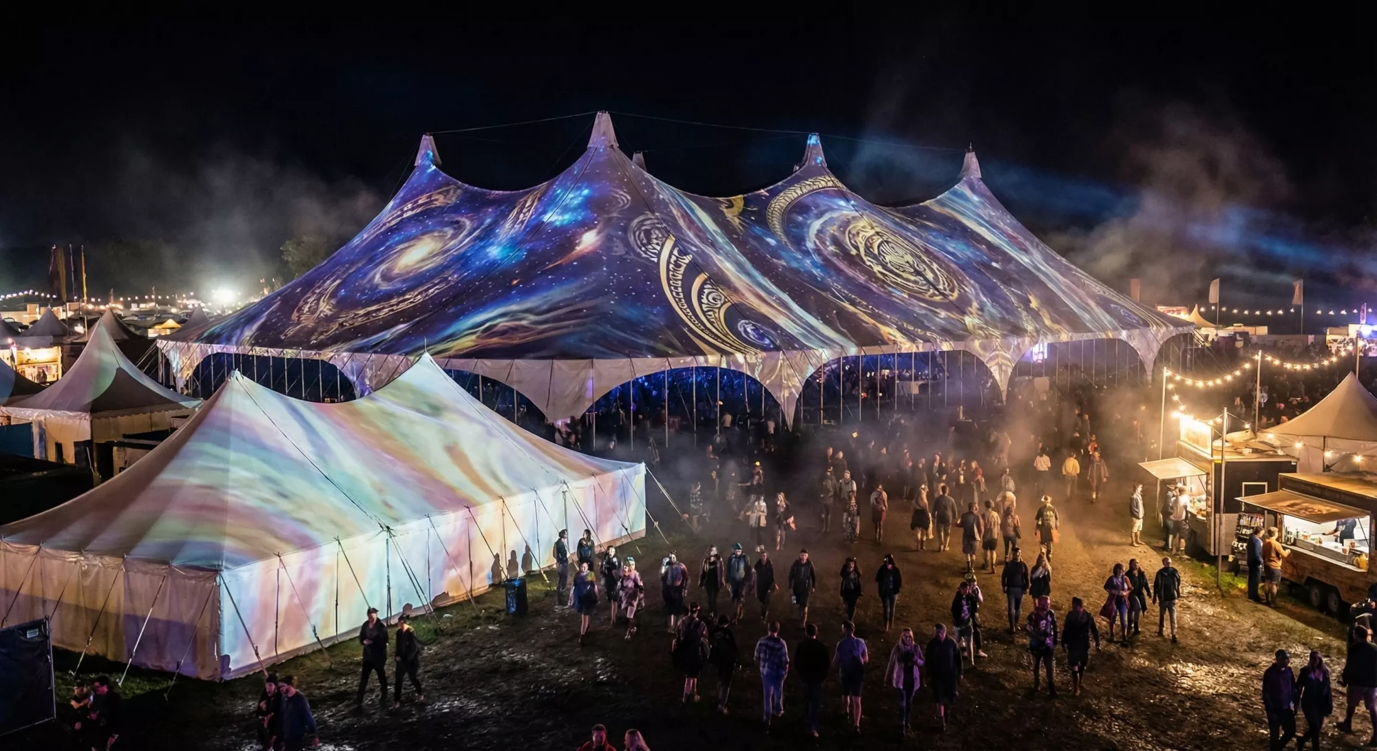 Festival tents illuminated with projection mapped patterns at night.