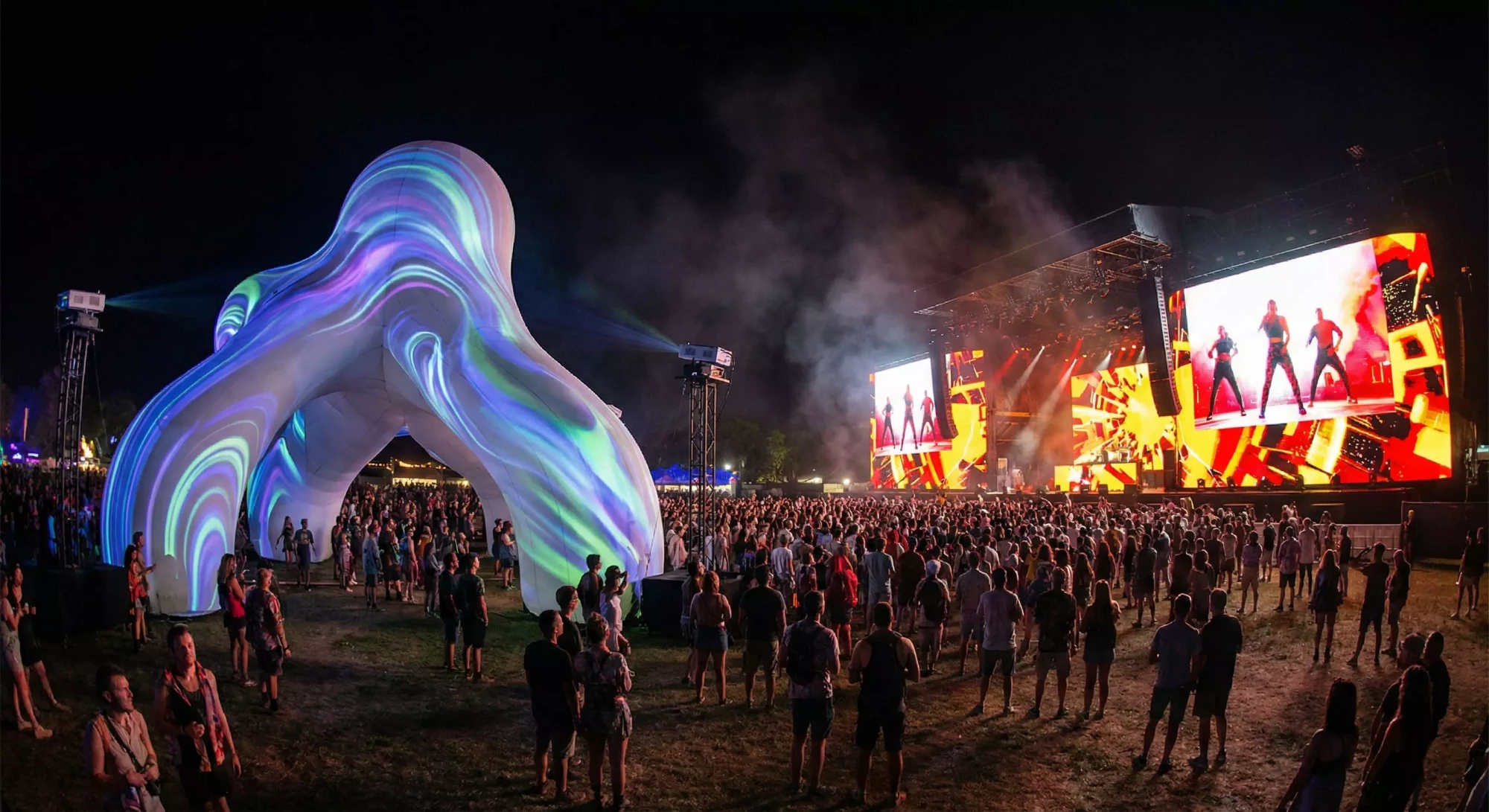 Projection-mapped sculpture contrasted with an LED wall on a festival stage.